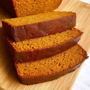 Freshly baked pumpkin bread loaf with spices and walnuts on a wooden table