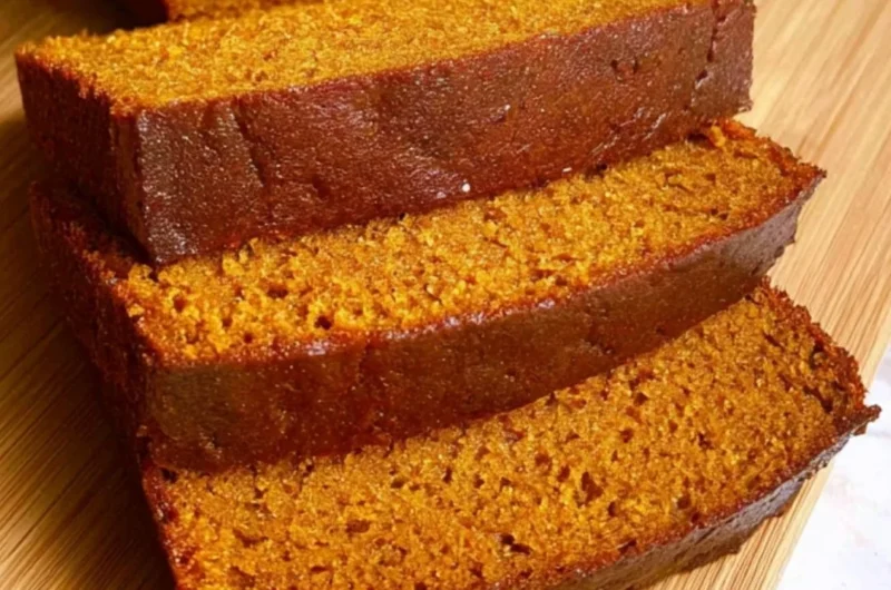 Freshly baked pumpkin bread loaf with spices and walnuts on a wooden table