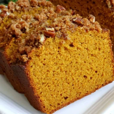 Loaf of cozy pumpkin bread fresh out of the oven with spices and autumn decor.