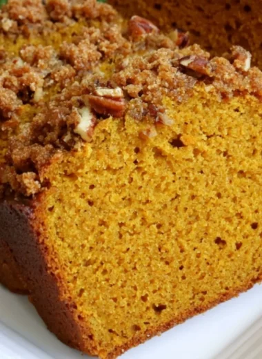 Loaf of cozy pumpkin bread fresh out of the oven with spices and autumn decor.