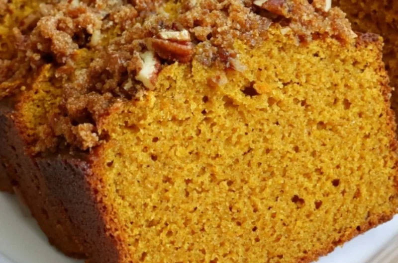 Loaf of cozy pumpkin bread fresh out of the oven with spices and autumn decor.