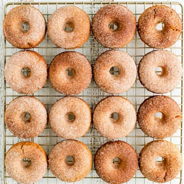 Freshly baked cozy pumpkin spice donuts topped with cinnamon sugar.