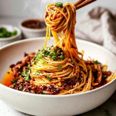 Bowl of cozy Szechuan noodles topped with fresh herbs and vegetables