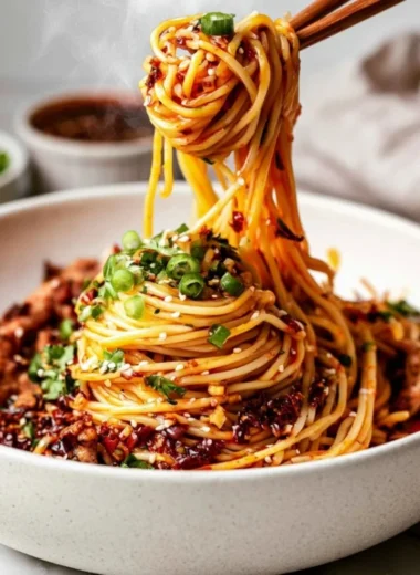 Bowl of cozy Szechuan noodles topped with fresh herbs and vegetables