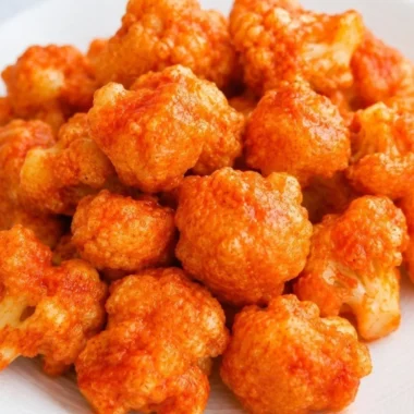 Baked vegan cauliflower nuggets served on a plate with dipping sauce.