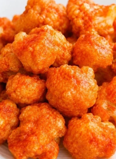 Baked vegan cauliflower nuggets served on a plate with dipping sauce.