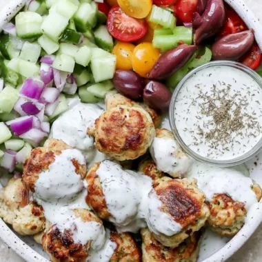 Plate of Greek Chicken Meatballs garnished with herbs and served with yogurt sauce