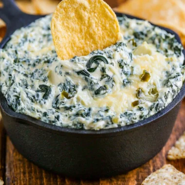 Warm and creamy spinach artichoke dip served in a bowl with chips
