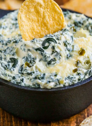 Warm and creamy spinach artichoke dip served in a bowl with chips