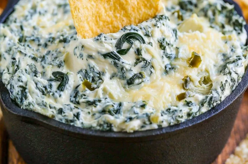 Warm and creamy spinach artichoke dip served in a bowl with chips