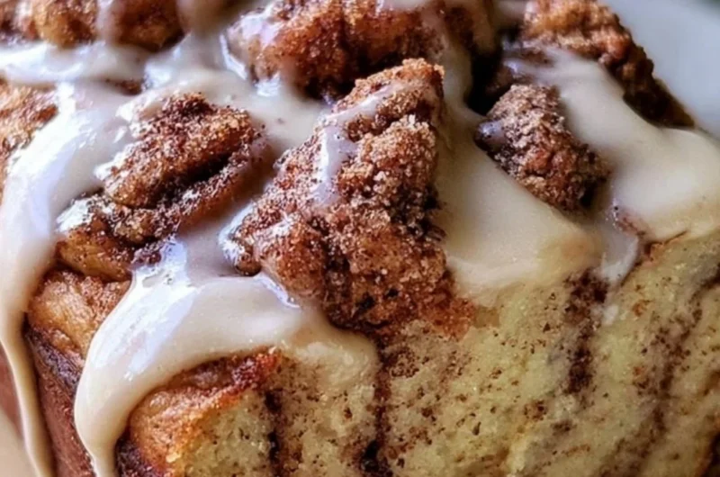 Cozy Cinnamon Roll Banana Bread topped with cinnamon glaze on a rustic wooden table