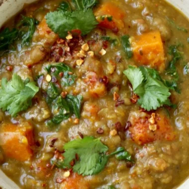 Bowl of earthy Moroccan Sweet Potato Lentil Stew garnished with herbs and spices.