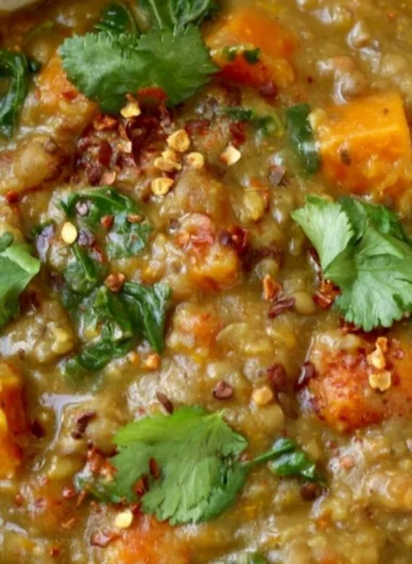 Bowl of earthy Moroccan Sweet Potato Lentil Stew garnished with herbs and spices.