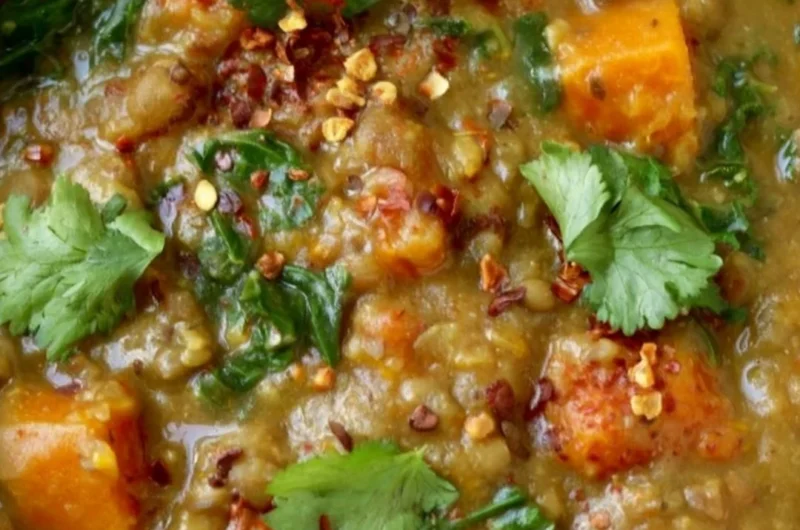 Bowl of earthy Moroccan Sweet Potato Lentil Stew garnished with herbs and spices.