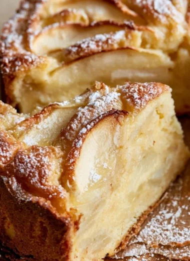 Golden and cozy French Apple Cake topped with fresh apples and a dusting of powdered sugar
