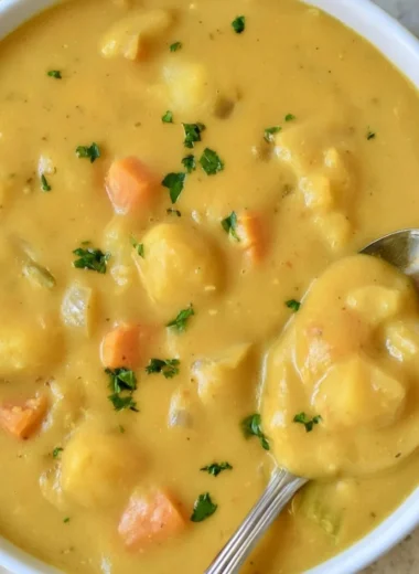 Bowl of German potato soup garnished with herbs and served hot.