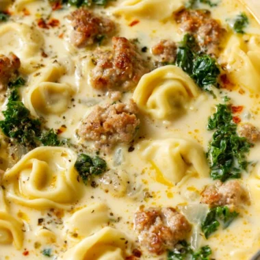 Delicious bowl of Sausage Tortellini Soup garnished with herbs and cheese